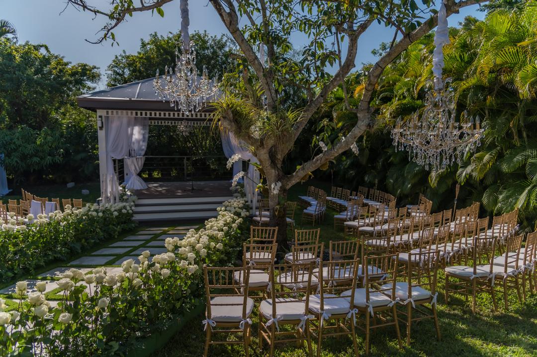 Garden ceremony with crystal chandeliers hanging from the trees, gold chairs and white roses