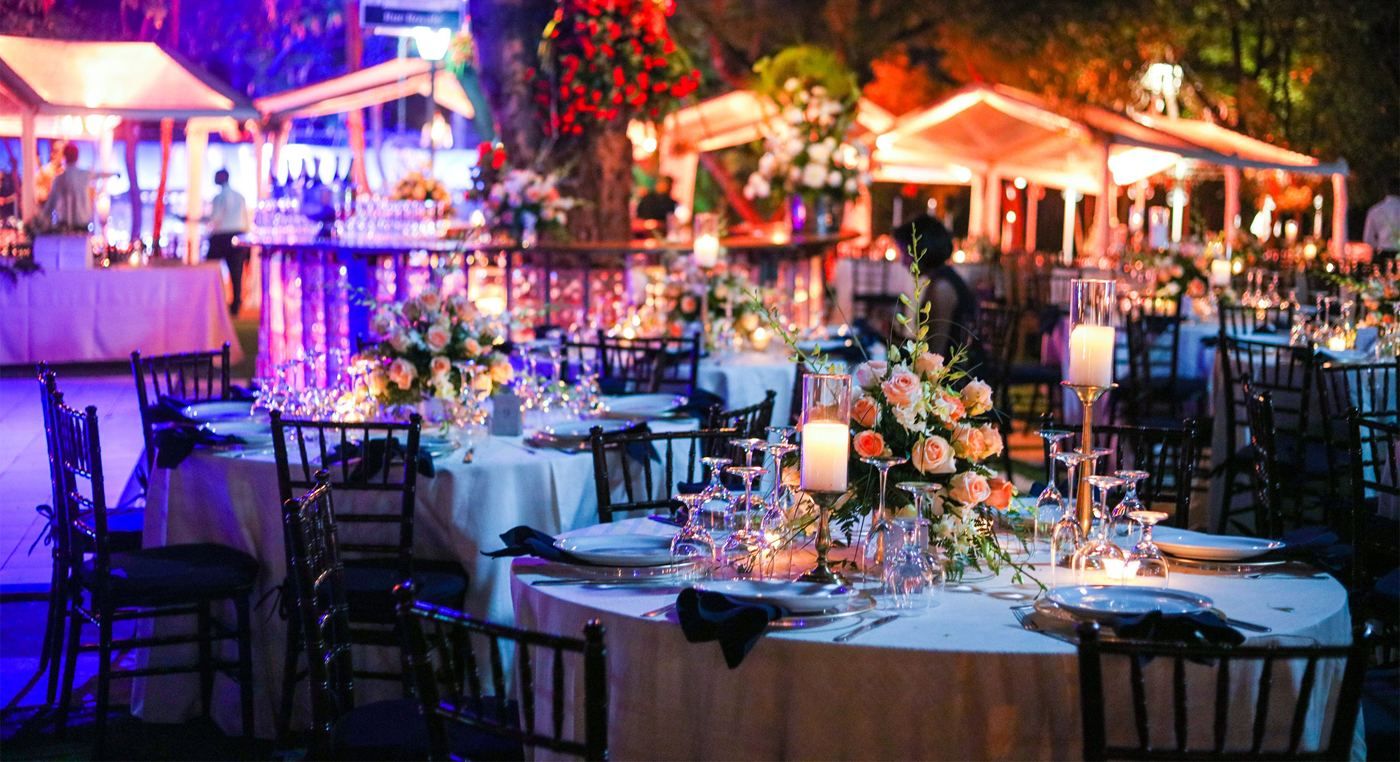 Evening outdoor reception with lit tables and floral arrangements