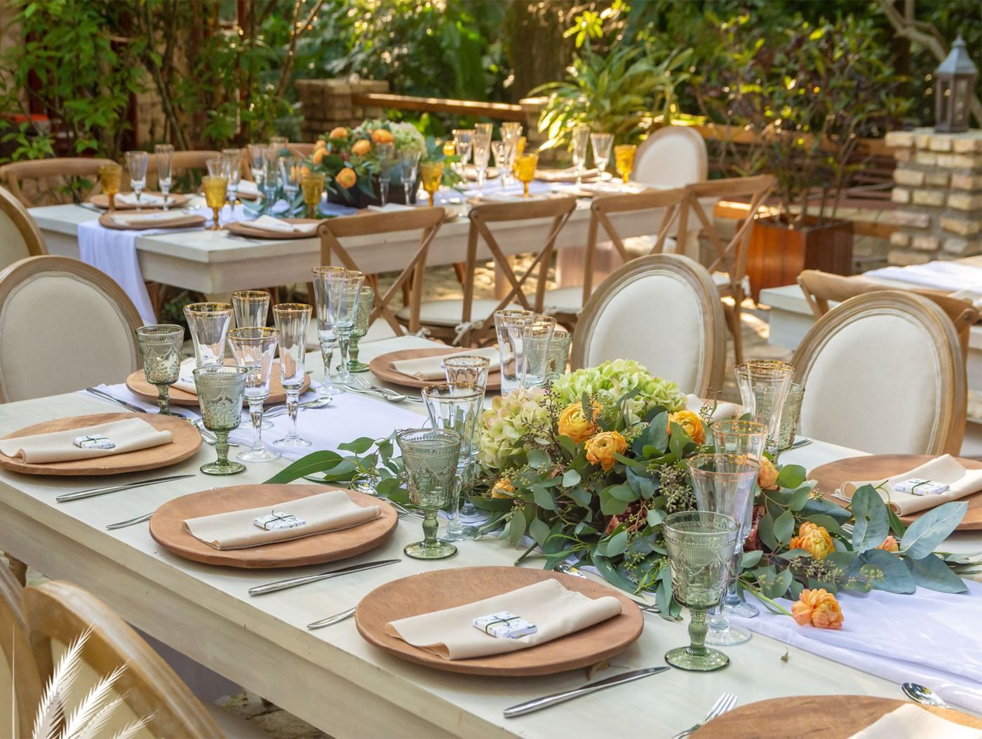 Table setting with woven chargers, green glassware and citrus florals